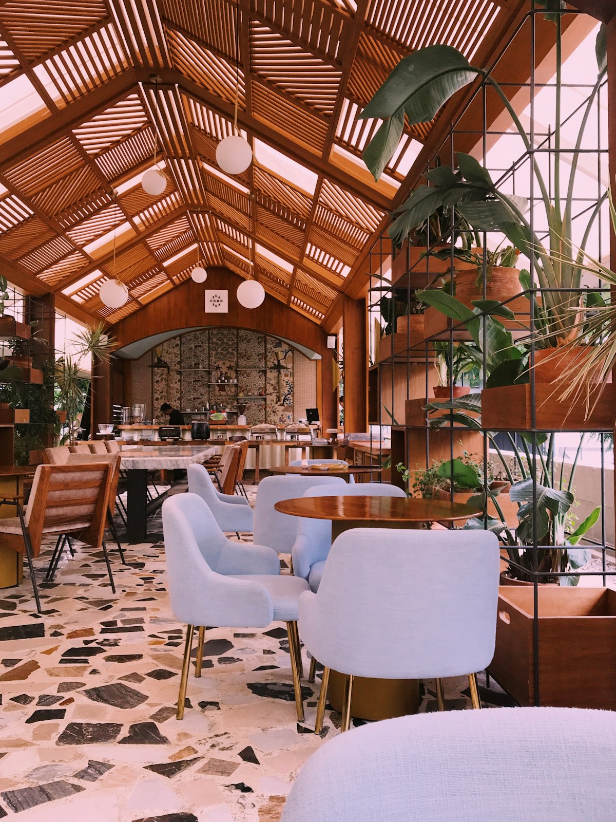 Interior luminoso de Cuadra, con plantas y mesas de madera