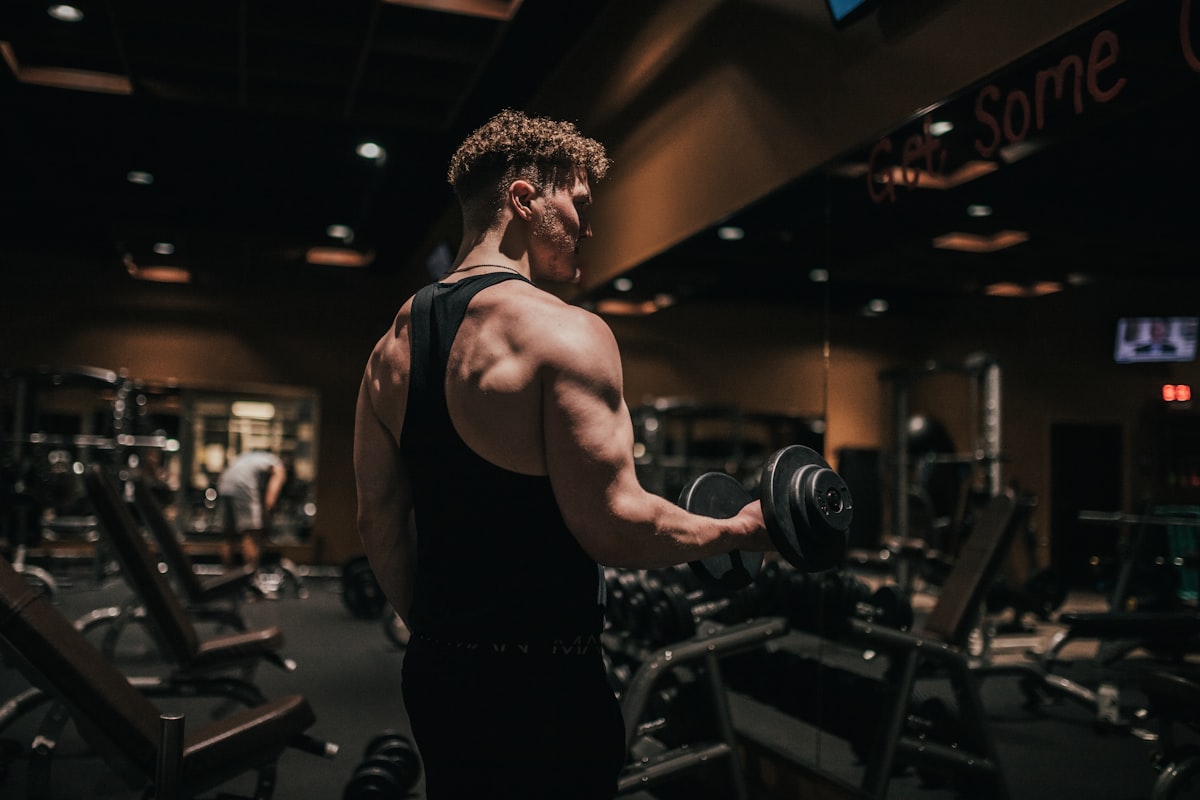 Entrenador haciendo curl de bíceps en gimnasio