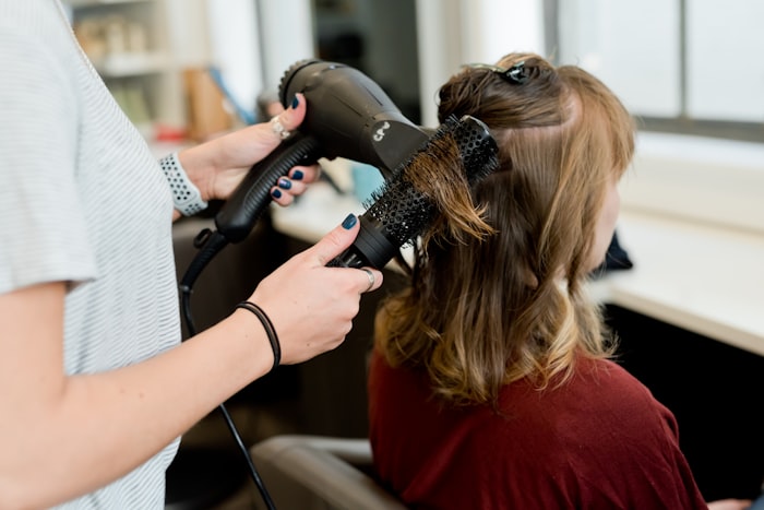 Estilista secando y peinando el cabello de una clienta