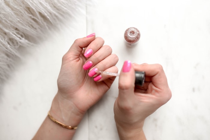 Manicure con esmalte rosa siendo aplicado